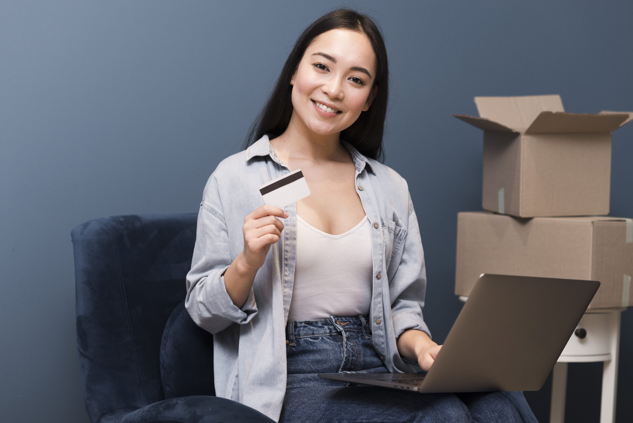 smiley woman posing with credit card laptop boxes scaled